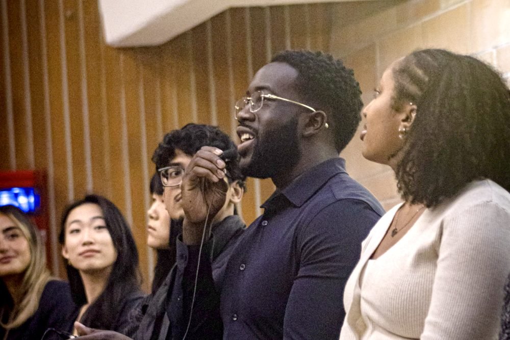 Ezekiel K. Bissah speaking into a microphone on the graduate school panel, alongside fellow panellists